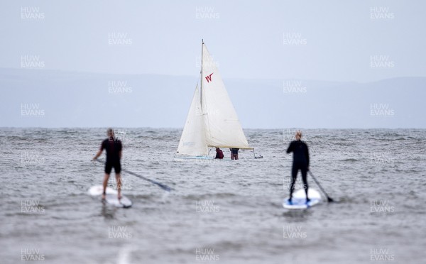 220620 - Picture shows paddle boarders and a sailing boat on the coast at Porthcawl on Monday morning, with temperatures set to sore later this week
