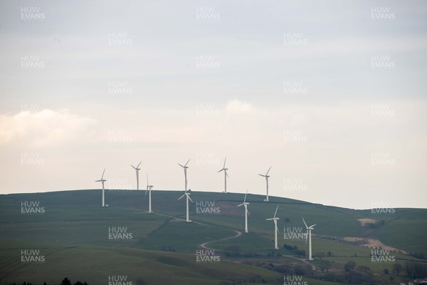 220422 - Picture shows a wind farm overlooking houses in Gilfach Goch, South Wales, UK The renewable energy is key for providing green energy to homes in the area as the Welsh Government pushes to net zero carbon emissions by 2050