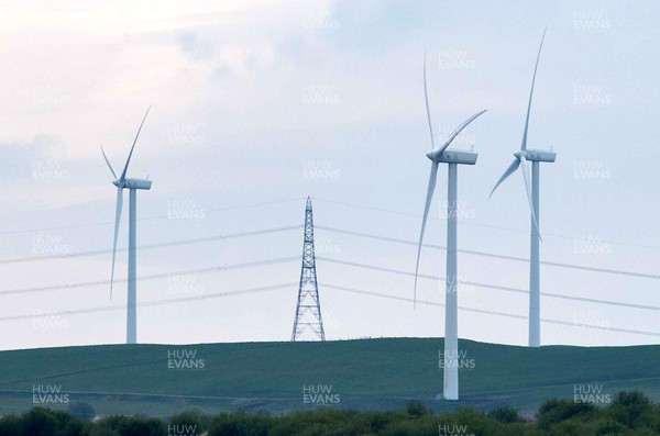 220422 - Picture shows wind turbines and an electricity pylon on a farm overlooking the village of Gilfach Goch, South Wales, UK The renewable energy is key for providing green energy to homes in the area as the Welsh Government pushes to net zero carbon emissions by 2050