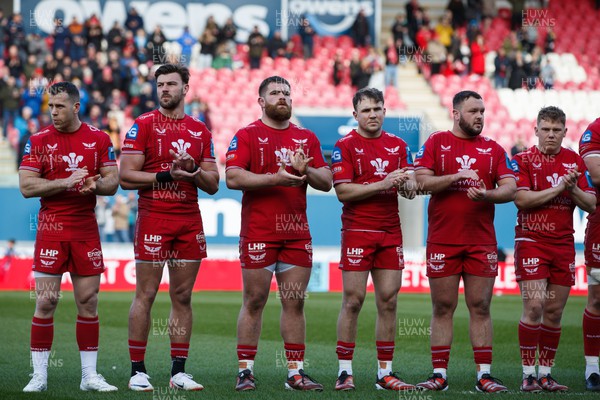 230324 - Scarlets v Benetton - United Rugby Championship - Gareth Davies, Johnny Williams, Kemsley Mathias, Ioan Lloyd, Harri O’Connor and Sam Costelow of Scarlets applaud in memory of Lewis Jones, former Llanelli and Wales player, before the match
