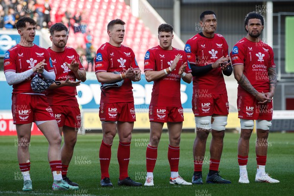 230324 - Scarlets v Benetton - United Rugby Championship -  Tom Rogers, Shaun Evans, Jonathan Davies, Tomi Lewis, Sam Lousi and Vaea Fifita of Scarlets applaud in memory of Lewis Jones, former Llanelli and Wales player, before the match
