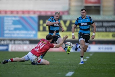 180426 - Scarlets v Cardiff Rugby - United Rugby Championship - Johan Mulder of Cardiff Rugby hacks ahead under pressure from Tom Rogers of Scarlets