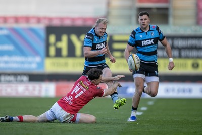180426 - Scarlets v Cardiff Rugby - United Rugby Championship - Johan Mulder of Cardiff Rugby hacks ahead under pressure from Tom Rogers of Scarlets