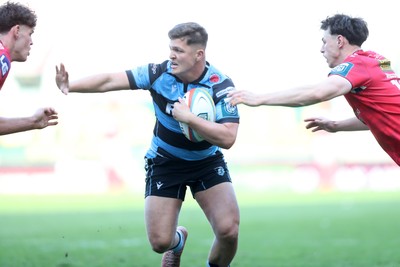 180426 - Scarlets v Cardiff Rugby - United Rugby Championship - Callum Sheedy of Cardiff Rugby hands off Eddie James of Scarlets 