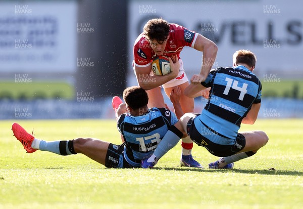 180426 - Scarlets v Cardiff Rugby - United Rugby Championship - Eddie James of Scarlets is tackled by Ben Thomas and Jacob Beetham of Cardiff 