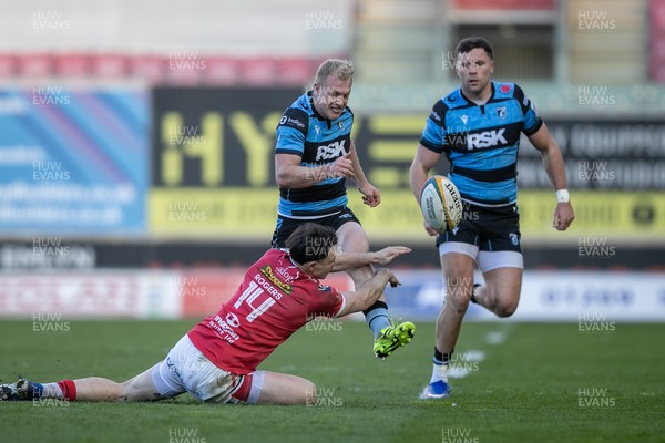 180426 - Scarlets v Cardiff Rugby - United Rugby Championship - Johan Mulder of Cardiff Rugby hacks ahead under pressure from Tom Rogers of Scarlets