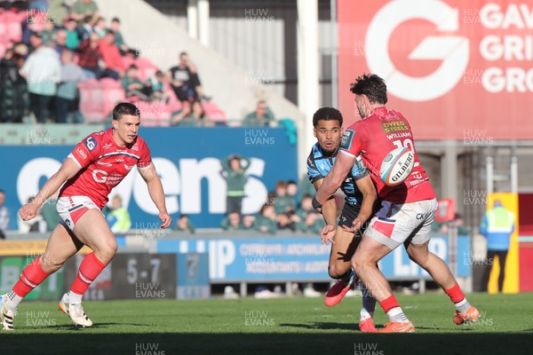 180426 - Scarlets v Cardiff Rugby - United Rugby Championship - Ben Thomas of Cardiff Rugby offloads from a tackle by Johnny Williams of Scarlets