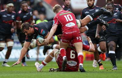 250323 - Scarlets v Cell C Sharks - United Rugby Championship - Eben Etzebeth of Sharks is tackled by Josh Macleod and Sam Costelow of Scarlets 