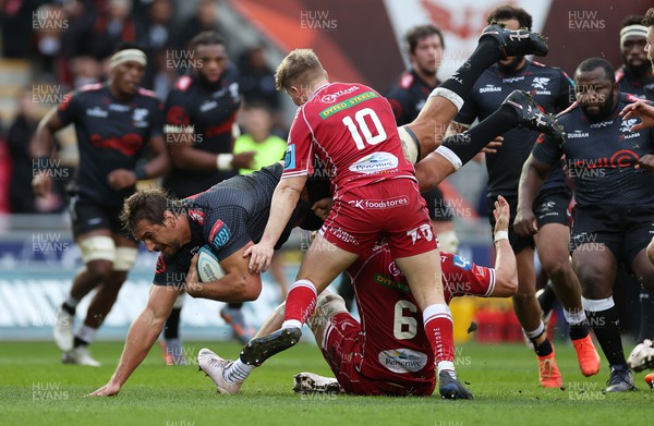 250323 - Scarlets v Cell C Sharks - United Rugby Championship - Eben Etzebeth of Sharks is tackled by Josh Macleod and Sam Costelow of Scarlets 