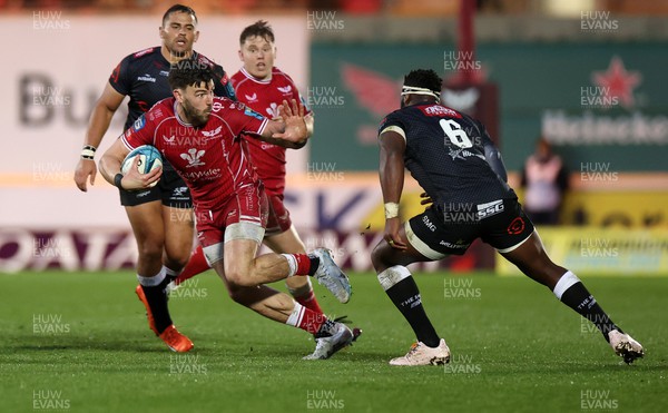 250323 - Scarlets v Cell C Sharks - United Rugby Championship - Johnny Williams of Scarlets is challenged by Siya Kolisi of Sharks 