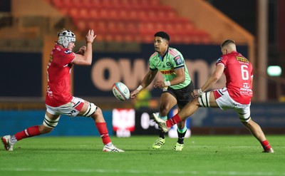 101025 - Scarlets v DHL Stormers, United Rugby Championship - Sacha Feinberg-Mngomezulu of Stormers chips the ball between Max Douglas of Scarlets and Jarrod Taylor of Scarlets