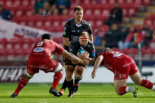 111123 - Scarlets v Emirates Lions - United Rugby Championship - PJ Botha of Lions is tackled by Carwyn Tuipulotu and Steff Thomas of Scarlets