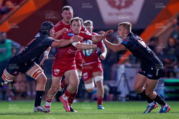 111123 - Scarlets v Emirates Lions - United Rugby Championship - Ioan Lloyd of Scarlets is tackled by Hanru Sirgel and Richard Kriel of Lions