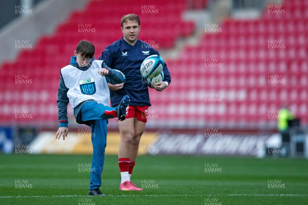 111123 - Scarlets v Emirates Lions - United Rugby Championship - Having invited ball boys onto the pitch before the warm up, Ioan Lloyd of Scarlets watches them practice their kicking