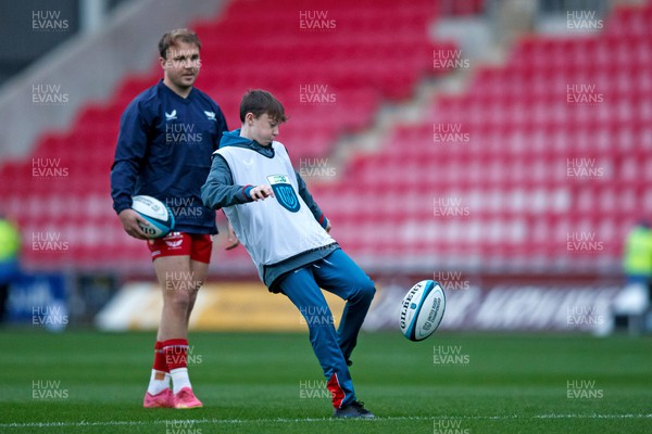111123 - Scarlets v Emirates Lions - United Rugby Championship - Having invited ball boys onto the pitch before the warm up, Ioan Lloyd of Scarlets watches them practice their kicking