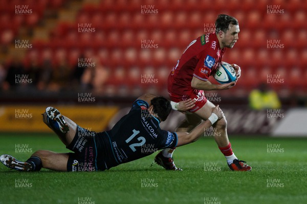 300324 - Scarlets v Glasgow Warriors - United Rugby Championship - Ioan Lloyd of Scarlets escapes the tackle of Tom Jordan of Glasgow