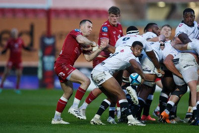 260424 - Scarlets v Hollywoodbets Sharks - United Rugby Championship - Under pressure from Gareth Davies of Scarlets, Grant Williams of Sharks throws a reverse pass