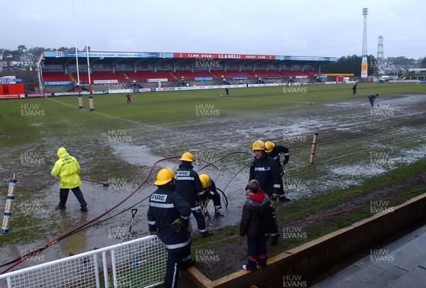 250306 - Llanelli Scarlets v Munster Fire Brigade and ground staff try to drain the waterlogged pitch at Stradey Park, before the match was postponed  