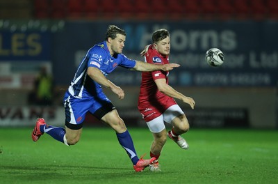 081016 - Scarlets v Newport Gwent Dragons, Guinness PRO12 - Steff Evans of Scarlets is challenged by Pat Howard of Newport Gwent Dragons as he kicks ahead