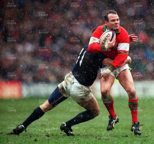 040395 - Scotland v Wales - Five Nations - Ieuan Evans of Wales is tackled by Kenny Logan of Scotland