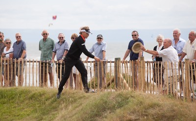 270714 -  The Senior Open Championship, Royal Porthcawl Golf Club, Wales - Bernhard Langer returns a hat to a spectator after it blow onto the green during the final round of the Senior Open at Royal Porthcawl Golf Club