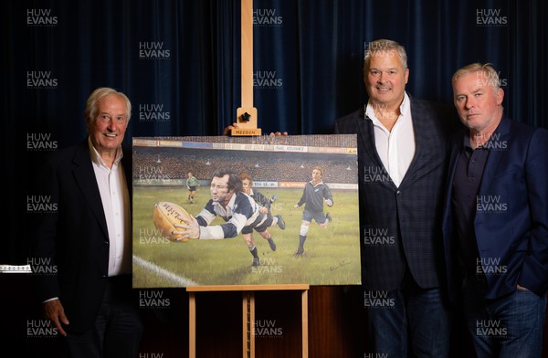 060722 - The Greatest Try Anniversary with Sir Gareth Edwards - Sir Gareth Edwards with Scott Salter and Adrian Davies with the specially commissioned painting of his 1973 Barbarian try against New Zealand to mark his 75th birthday, 50th wedding anniversary and 50 years since scoring “The Greatest Try” 