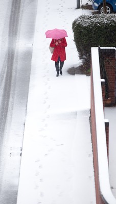 180113 - Snow hits south Wales -A worker makes her way through the snow in Cardiff