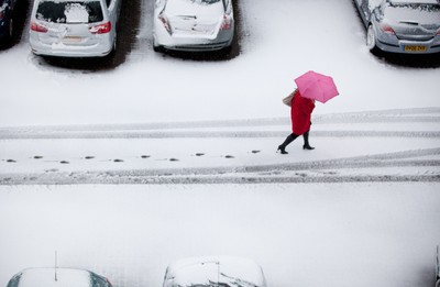 180113 - Snow hits south Wales -A worker makes her way through the snow in Cardiff