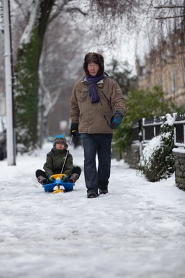 180113 - Snow hits south Wales -A young boy takes advantage of his sledge as he's pulled through the snow in Cardiff