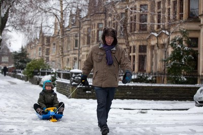 180113 - Snow hits south Wales -A young boy takes advantage of his sledge as he's pulled through the snow in Cardiff