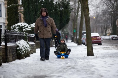 180113 - Snow hits south Wales -A young boy takes advantage of his sledge as he's pulled through the snow in Cardiff