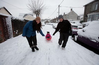 180113 - Snow hits south Wales -Grace Mantle, aged 5 from Mountain Ash, gets a tow from parents Phil and Lynsey as they head off sledging in the snow