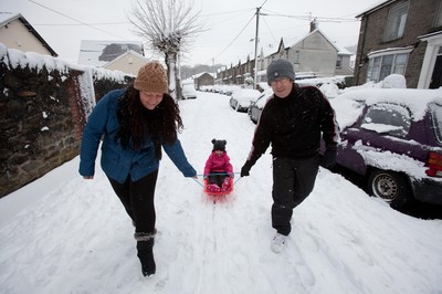 180113 - Snow hits south Wales -Grace Mantle, aged 5 from Mountain Ash, gets a tow from parents Phil and Lynsey as they head off sledging in the snow