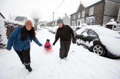 180113 - Snow hits south Wales -Grace Mantle, aged 5 from Mountain Ash, gets a tow from parents Phil and Lynsey as they head off sledging in the snow