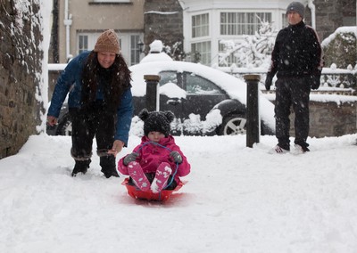 180113 - Snow hits south Wales -Grace Mantle, aged 5 from Mountain Ash, tries out her sledge as parents Phil and Lynsey look on