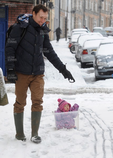 180113 - Heavy Snowfall in South Wales -A man finds an alternative way to tow his baby in the snow in Penarth near Cardiff following heavy snowfall in South Wales