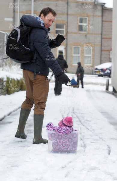 180113 - Heavy Snowfall in South Wales -A man finds an alternative way to tow his baby in the snow in Penarth near Cardiff following heavy snowfall in South Wales