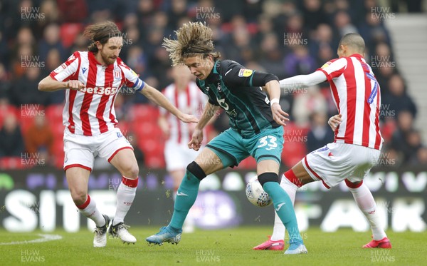 250120 - Stoke City v Swansea City - Sky Bet Championship - Conor Gallagher  of Swansea tries to go through Thomas Ince of Stoke City and Joe Allen of Stoke City   