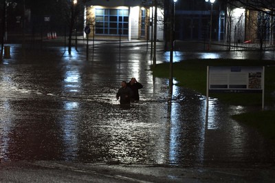 160220 - South Wales Flooding during Storm Dennis - Two men walk through flood water in Nantgarw, South Wales