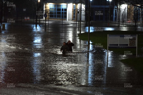 160220 - South Wales Flooding during Storm Dennis - Two men walk through flood water in Nantgarw, South Wales