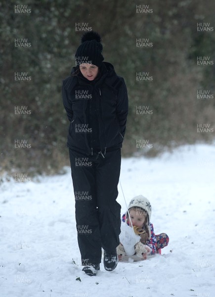 020318 - Weather - A woman tries to drag he child's sledge in Penarth near Cardiff, South Wales after being hit by Storm Emma