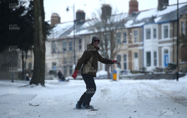 020318 - Weather - A man uses his snowboard to get around in Penarth near Cardiff, South Wales after being hit by Storm Emma