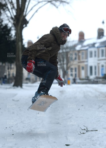 020318 - Weather - A man uses his snowboard to get around in Penarth near Cardiff, South Wales after being hit by Storm Emma