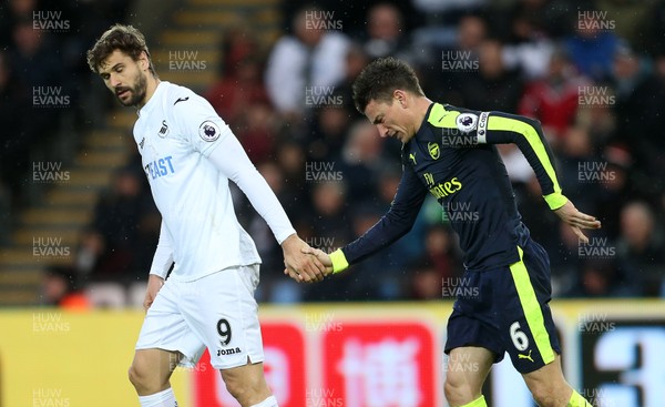 140117 - Swansea City v Arsenal - Premier League - Fernando Llorente of Swansea City helps Laurent Koscielny of Arsenal off the ground by Chris Fairweather/Huw Evans Agency