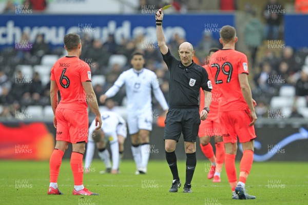 220220 - Swansea City v Huddersfield Town, Sky Bet Championship - Referee Andy Davies shows the yellow card to Jonathan Hogg of Huddersfield Town (left)