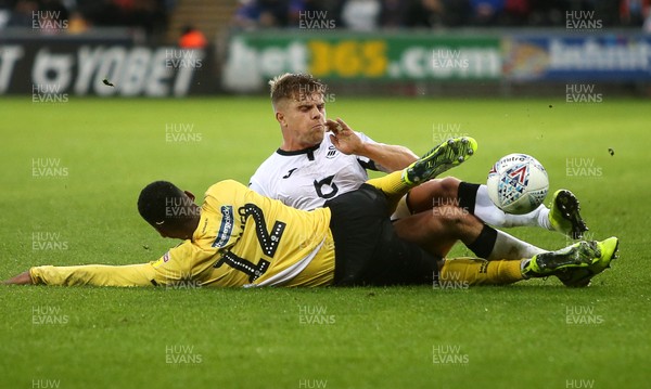 231119 - Swansea City v Millwall - SkyBet Championship - Mahlon Romeo of Millwall and Jake Bidwell of Swansea City collide going for the ball