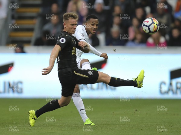 100917 - Swansea City v Newcastle United, Premier League - Martin Olsson of Swansea City plays the ball forward as Matt Ritchie of Newcastle United challenges