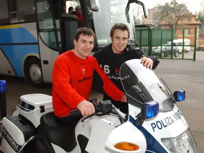 140203 - Wales Rugby in Italy - Welsh rugby players Iestyn Harris and Rhys Williams try out one of the police motorbikes with one of the Italian police officers used to escort the team bus