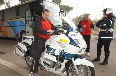 140203 - Wales Rugby in Italy - Welsh rugby coach Steve Hansen tries out a police outriders motorbike as the team prepare to leave the ground after training in Rome