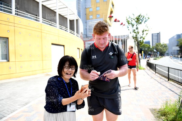 150919 - Wales Rugby Training and Media Interviews - Rhys Carre signs autographs for a local as he walks through the streets of Kitakyushu to training